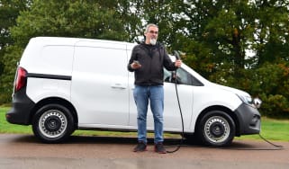 Auto Express senior test editor Dean Gibson standing next to our long-term Renault Kangoo E-Tech and holding a charging cable